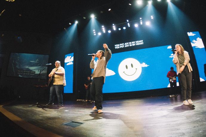 a group of people standing on top of a stage at the front of led wall